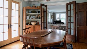 A dining area with a wooden table and chairs, a built-in cabinet with shelves, and a view into the kitchen. - Centrally located, a Beautiful Landmark House for an ideal Family Getaway! (Burlington)