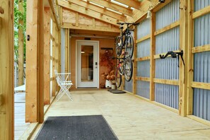 A wooden structure with a door, a bicycle rack, and a chair.