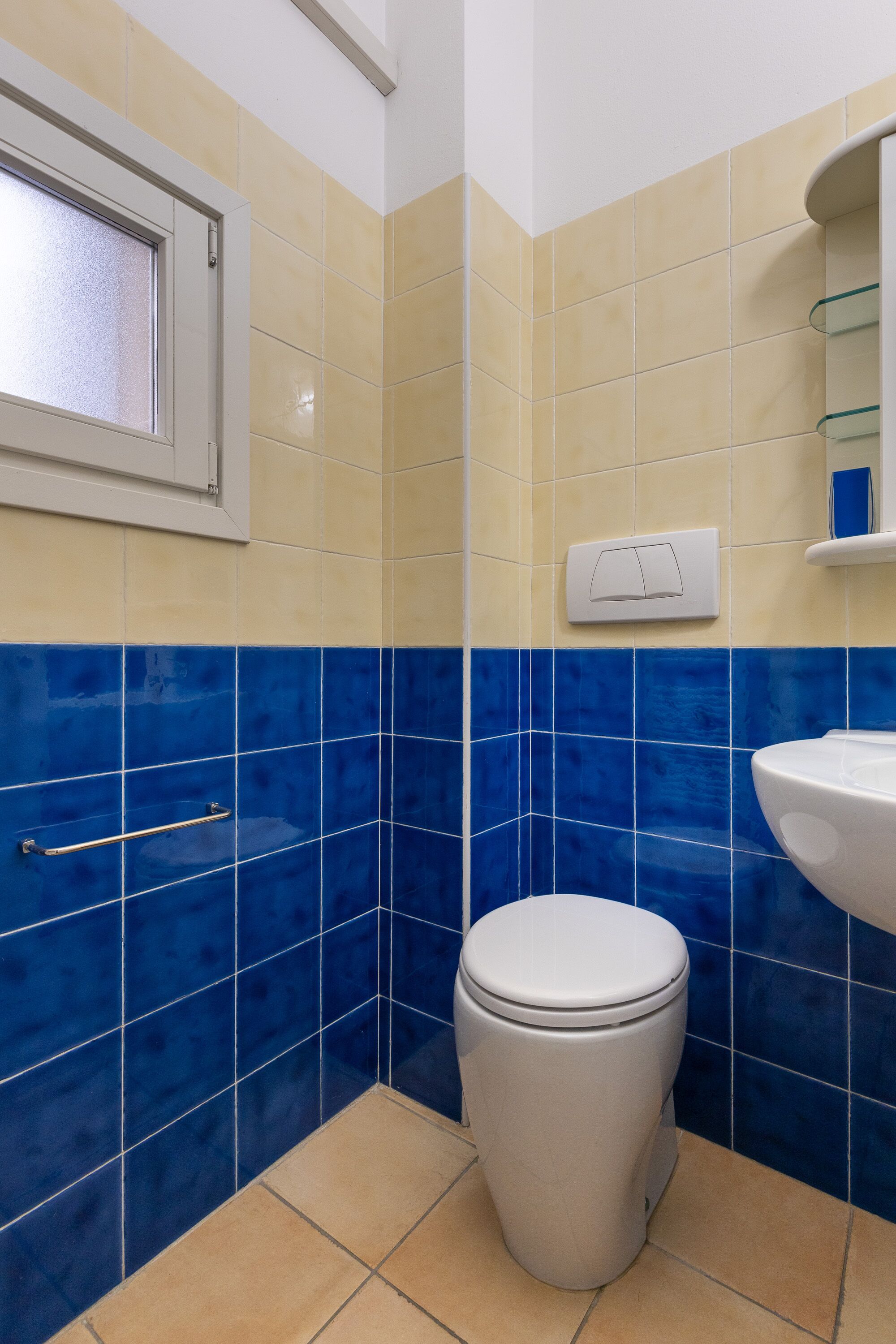 A bathroom with a toilet, a sink, and a window.