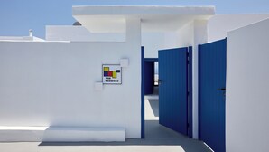 A modern building with a white exterior and blue doors, featuring a sign that reads "Villa Thardeos." - Thadeos Villa (Santorini)