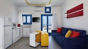 A compact living space with a kitchenette, a sofa, and a TV. - Thadeos Villa (Santorini)