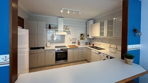 A modern kitchen with white cabinets, a central island, and a built-in oven. - Preciosa Vivienda Para Vacaciones a 50m de la Playa de Altar (Barreiros)