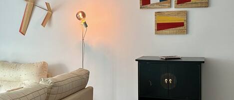 Una sala de estar moderna con un sofá, un banco de madera, un mueble negro y decoración en la pared.