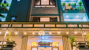 A building with a modern facade, a staircase leading to the entrance, and potted plants around the entrance area. - Vinh Khang Homestay (Da Nang)