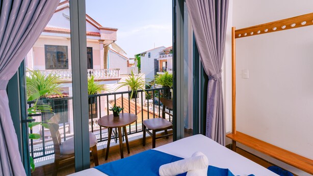A hotel room with a balcony, a bed, a small table, and chairs. - Vinh Khang Homestay (Da Nang)
