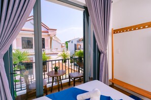 Een hotelkamer met balkon, een bed, een tafeltje en stoelen.