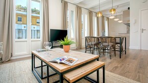 A modern living room with a wooden coffee table, a potted plant, and a flat-screen TV. - Genteel Home Almirante Lobo II (Sevilla)