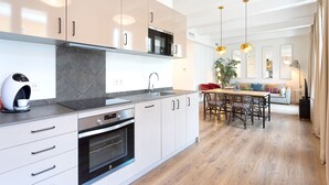 A modern kitchen with stainless steel appliances, a marble backsplash, and a wooden dining area with a plant. - Genteel Home Almirante Lobo II (Sevilla)