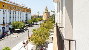 A street view with a prominent tower, a café area, and a building with a yellow facade. - Genteel Home Almirante Lobo II (Sevilla)