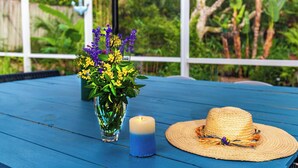 Ein blauer Tisch mit einer Blumenvase, einer Kerze und einem Strohhut.