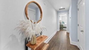 Un pasillo con un banco de madera, un espejo y una planta decorativa.
