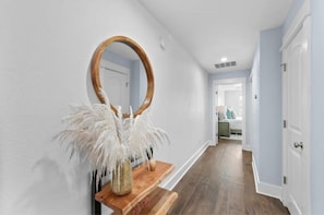 A hallway with a wooden bench, a mirror, and a decorative plant.
