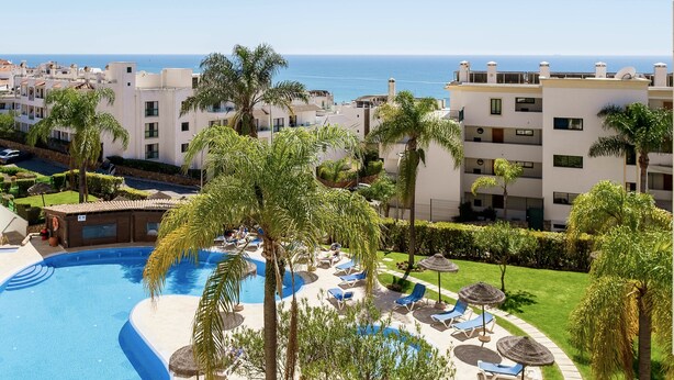 Ett semesterparadis med en swimmingpool, palmer och utsikt över havet.