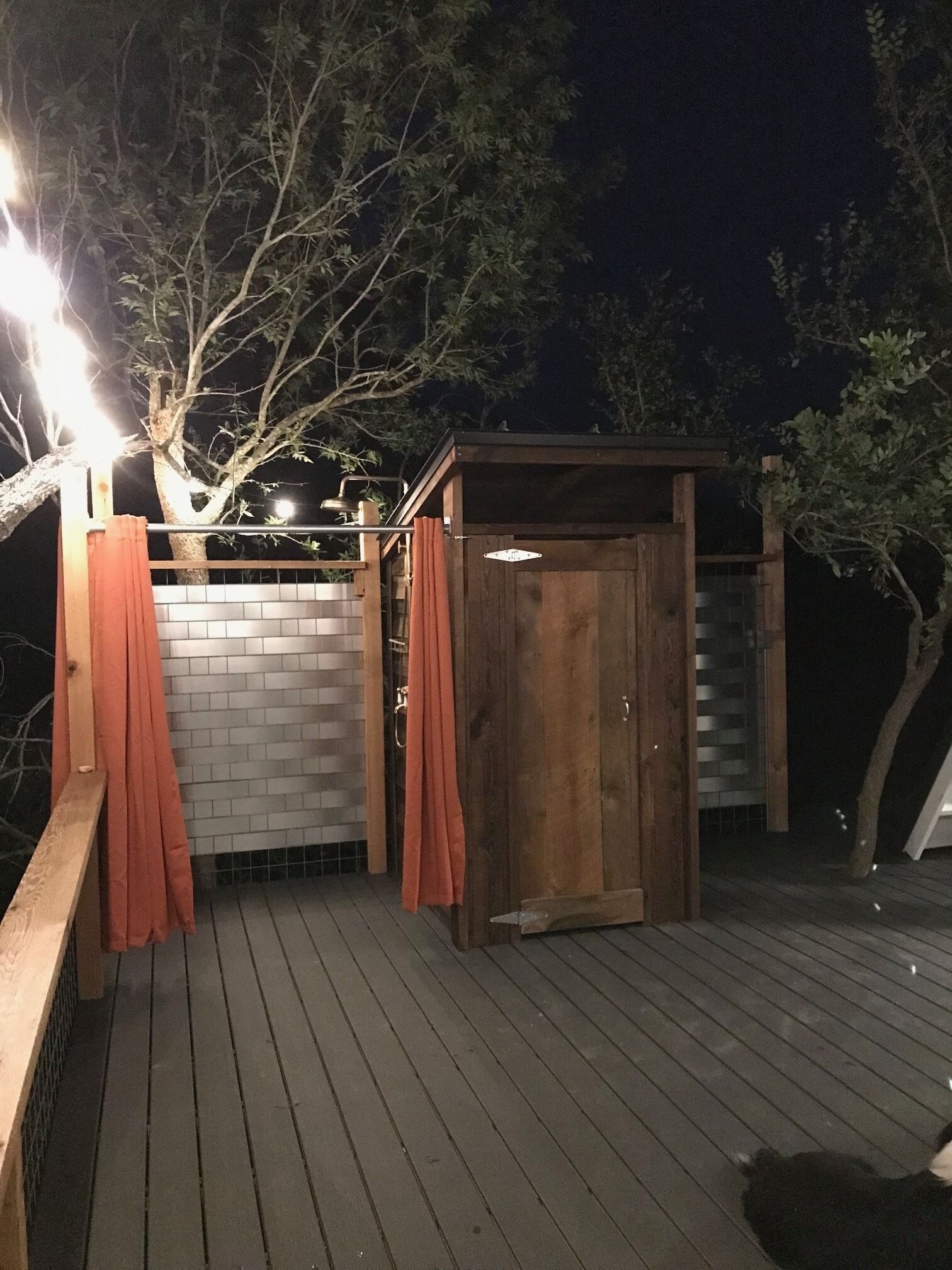 Una terraza de madera con un cobertizo pequeño y un muro de ladrillo.