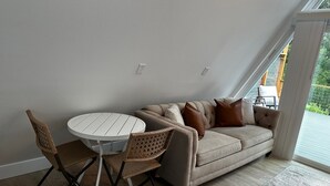 En moderne stue med en beige sofa, et rundt hvidt bord og fletstole.