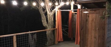 Eine Holzterrasse mit Hund, Lichterketten und einer Holzkonstruktion.
