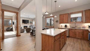 A modern kitchen with wooden cabinets, a granite countertop, and pendant lighting.