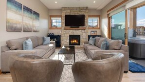 A living room with a stone fireplace, two sofas, a coffee table, and a flat-screen TV.