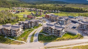 A residential area with multi-story buildings, a winding road, and a mountainous backdrop.