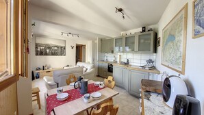 A compact living space with a dining area, kitchenette, and a sofa in the living room. - Apartment 4 to 5 pers mountain view Grand Cerf 67 (Saint-Jean-d´Aulps)