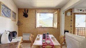 A cozy room with a wooden interior, a dining table set with plates, cups, and a kettle, and a window offering a mountain view. - Apartment 4 to 5 pers mountain view Grand Cerf 67 (Saint-Jean-d´Aulps)