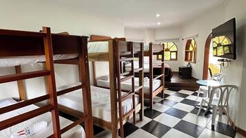 A hotel room with bunk beds, a checkered floor, a television, and a small table with chairs.