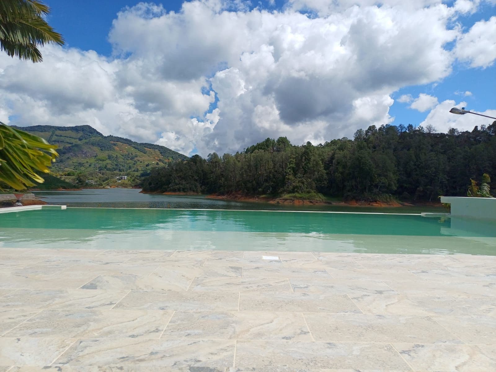 A swimming pool with a view of a lake and forested hills.