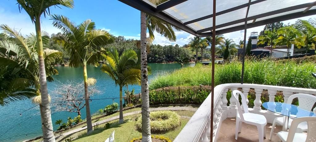 A covered outdoor area with a table and chairs, overlooking a body of water and greenery.