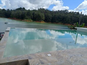 Una piscina con vistas a un lago y colinas boscosas.