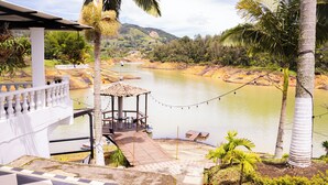 A riverside view with a gazebo, palm trees, and a checkered floor. - Casa Linda Guatapé (Guatapé)