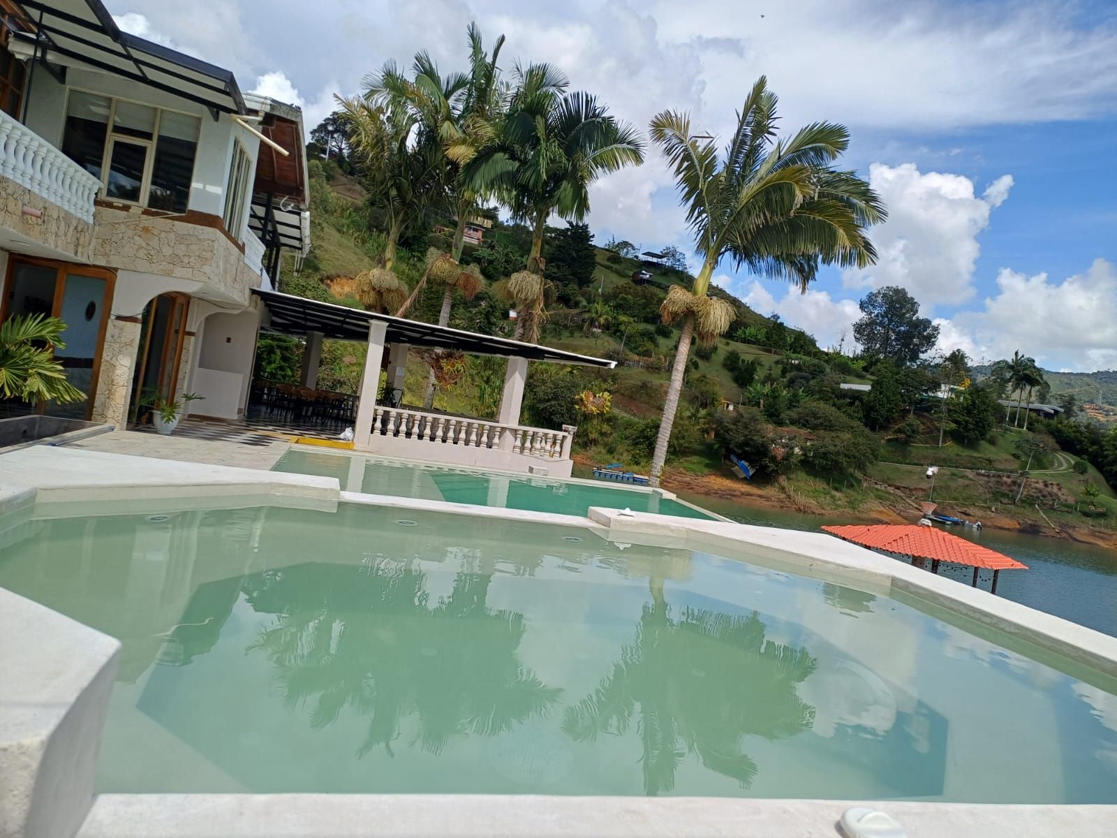 A swimming pool with a view of a house and palm trees.