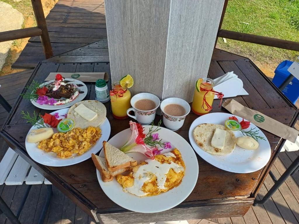 A wooden table with breakfast plates, including scrambled eggs, toast, and a beverage.