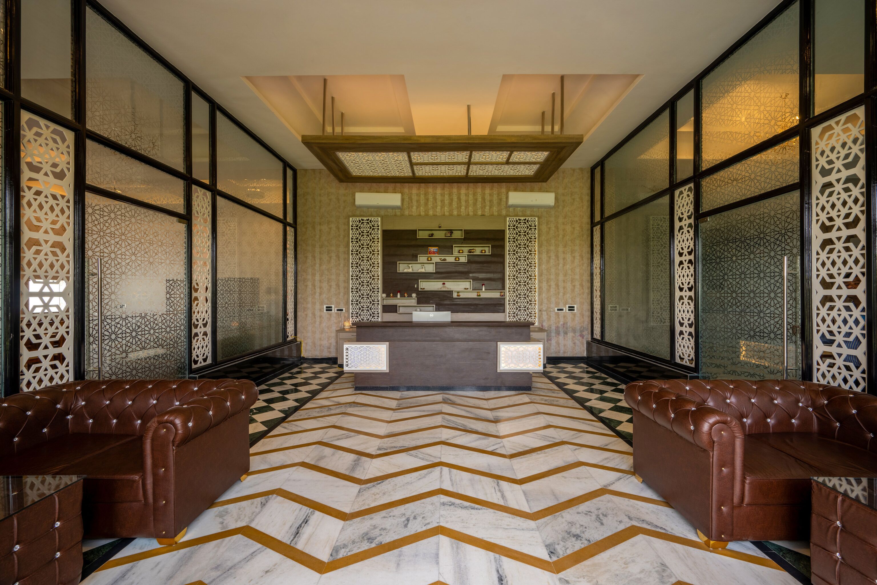 Un hall d’entrée avec un sol à carreaux, un comptoir de réception et deux canapés en cuir.
