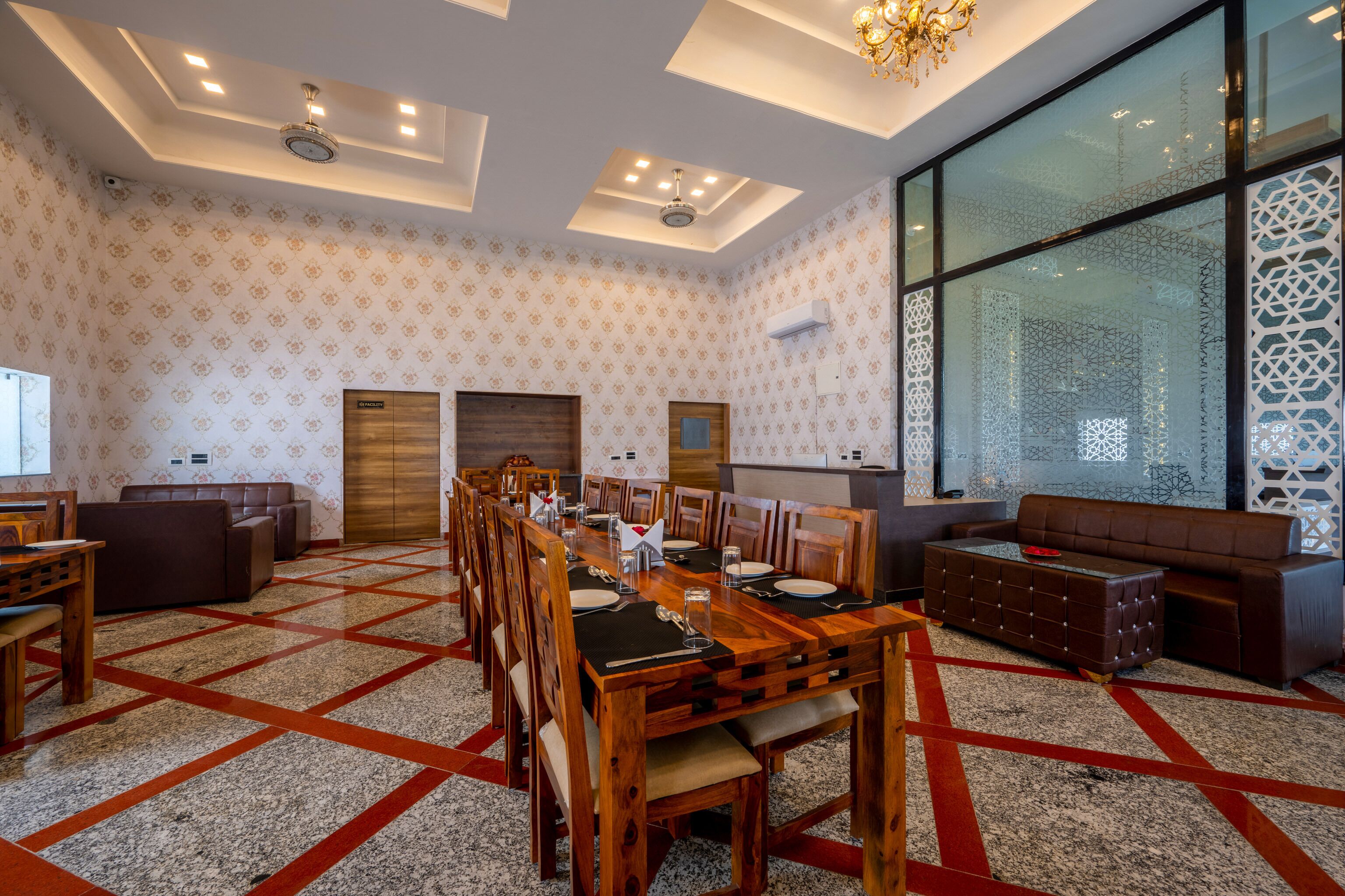 A spacious dining area with a long wooden table, multiple chairs, and a large window with decorative glass panels.