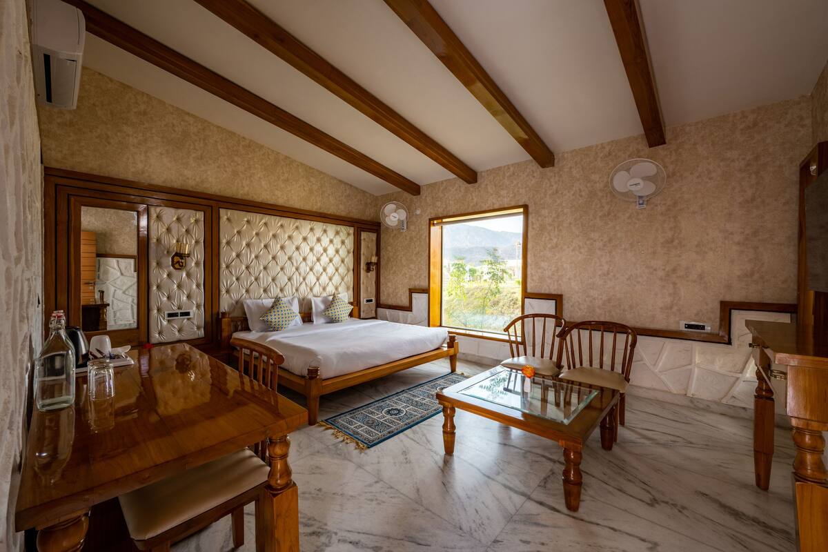 Ein Schlafzimmer mit einem Bett, Holzmöbeln, einem großen Fenster und Blick ins Freie.