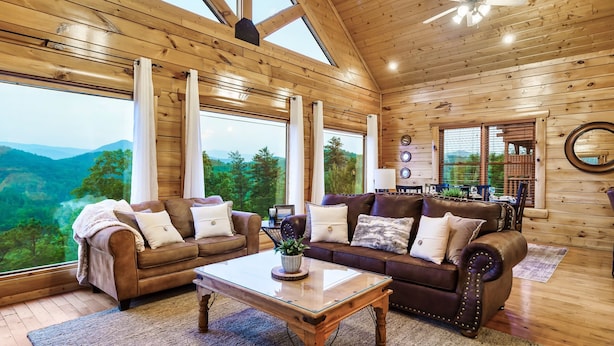 A spacious living room with wooden walls and large windows offering a view of the mountains. - Mega Views! 6 Miles to GSMNP! Hot Tub, Pool Table, Arcade, Foosball, 2Kg, 2QN (Sevierville)