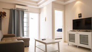 Un salon moderne comprenant un canapé, une table, un téléviseur et un appareil de climatisation.