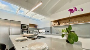 Een moderne keuken met een centraal eiland, roestvrijstalen apparatuur en een dakraam.