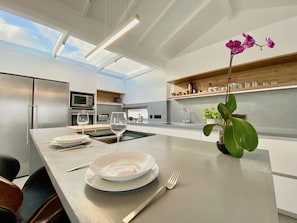 A modern kitchen with a central island, stainless steel appliances, and a skylight.