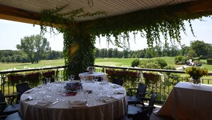 An outdoor dining area with tables set for a meal, overlooking a golf course. - Golf Hotel Castelconturbia (Agrate Conturbia)