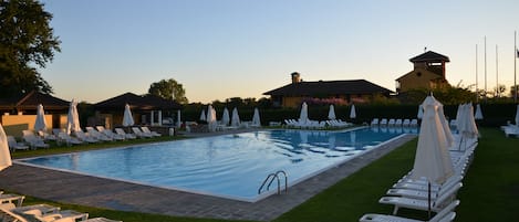 Una piscina al aire libre de temporada, sombrillas, tumbonas