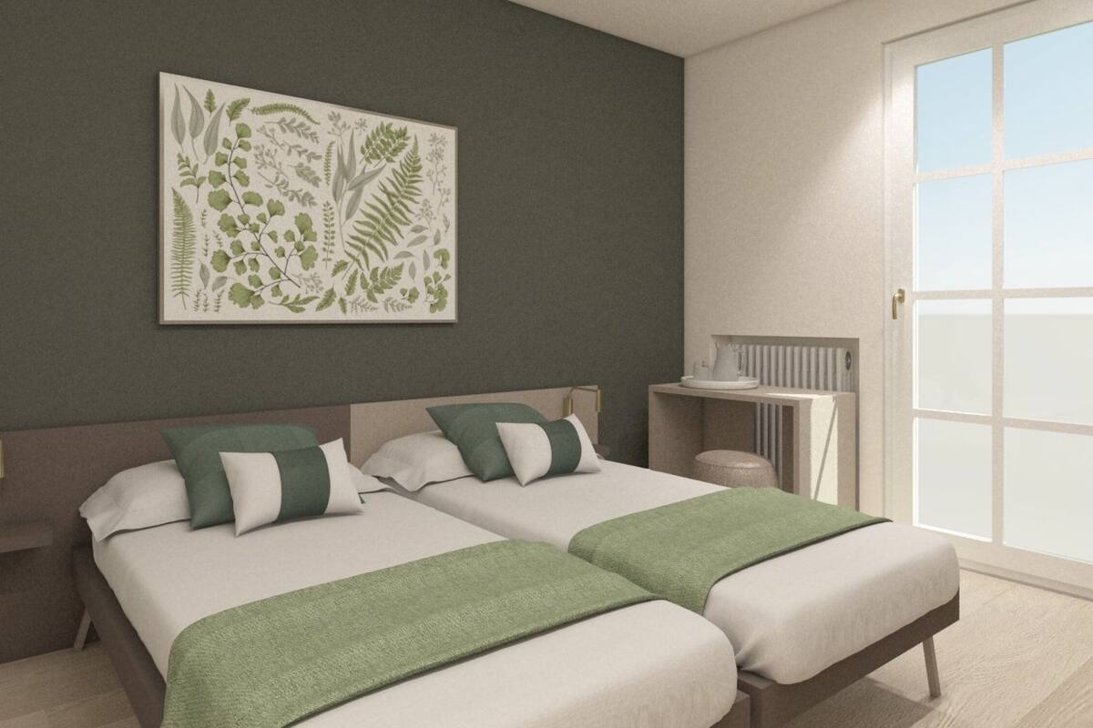 Ein Schlafzimmer mit zwei Betten, einer Farbgestaltung in Grün und Weiß, einem Heizkörper und einem Fenster.
