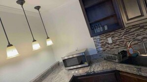 A kitchen with pendant lighting, a microwave, and a sink.