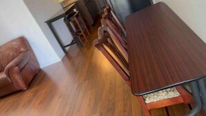 A wooden dining table with a cushioned bench, a leather chair, and a small stool in a room with wooden flooring.