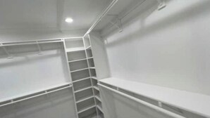 A white closet with shelves and a ladder.