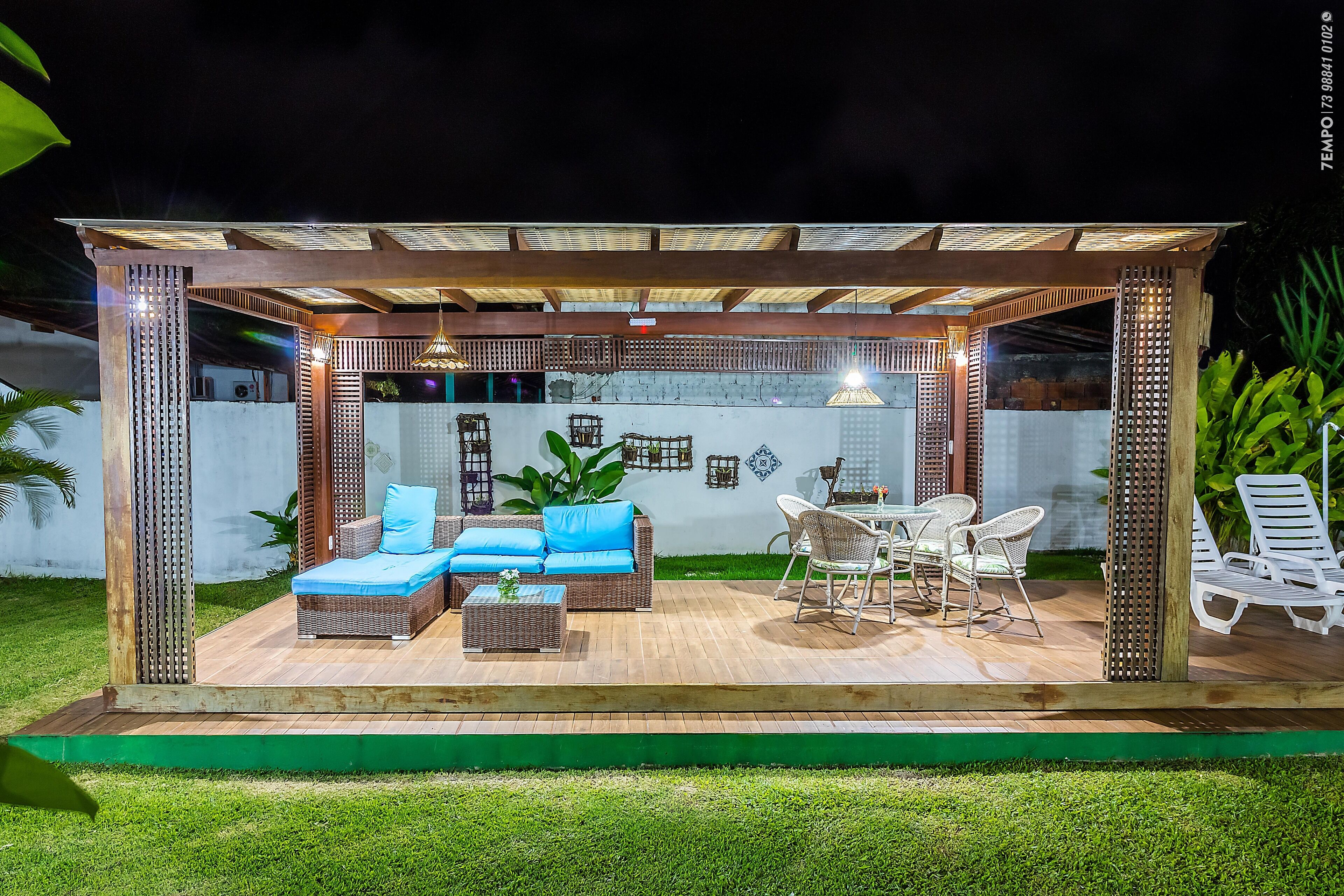 An outdoor patio with wicker furniture, a dining table, and a ceiling structure.