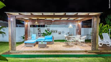 Una terrazza esterna con mobili in vimini, un tavolo da pranzo e una struttura per il soffitto.