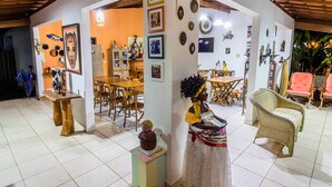 A spacious living area with a dining table, chairs, and a sofa. - Pousada Galeão Santa Anna (Maraú)