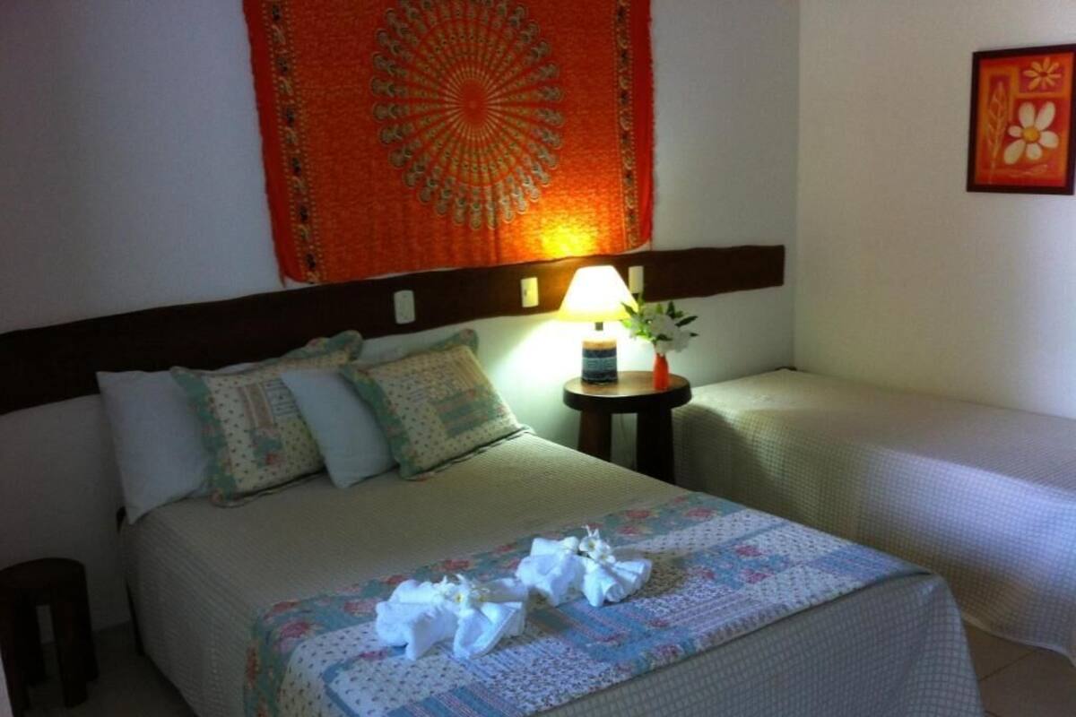A hotel room with a bed, a nightstand with a lamp, and a wall tapestry.