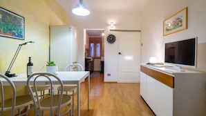 A modern kitchen with a dining area, wooden flooring, and a TV on the counter. - Santa Reparata Flat by Mmega (Florence)